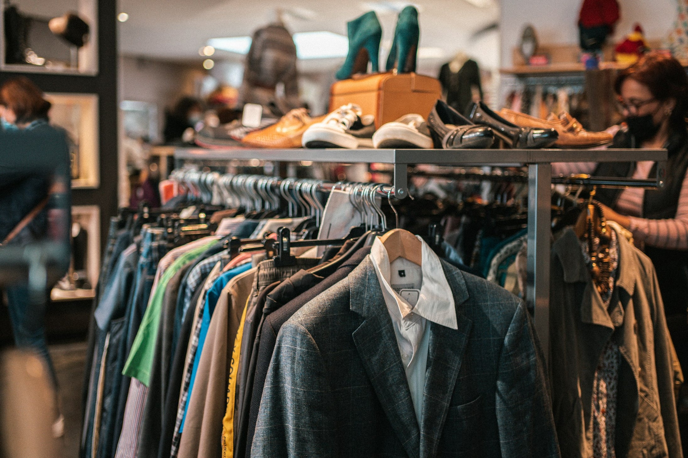 A rail of clothing and a shelf of shoes in a multi-brand retail store, representing the wholesale channel alongside direct-to-consumer