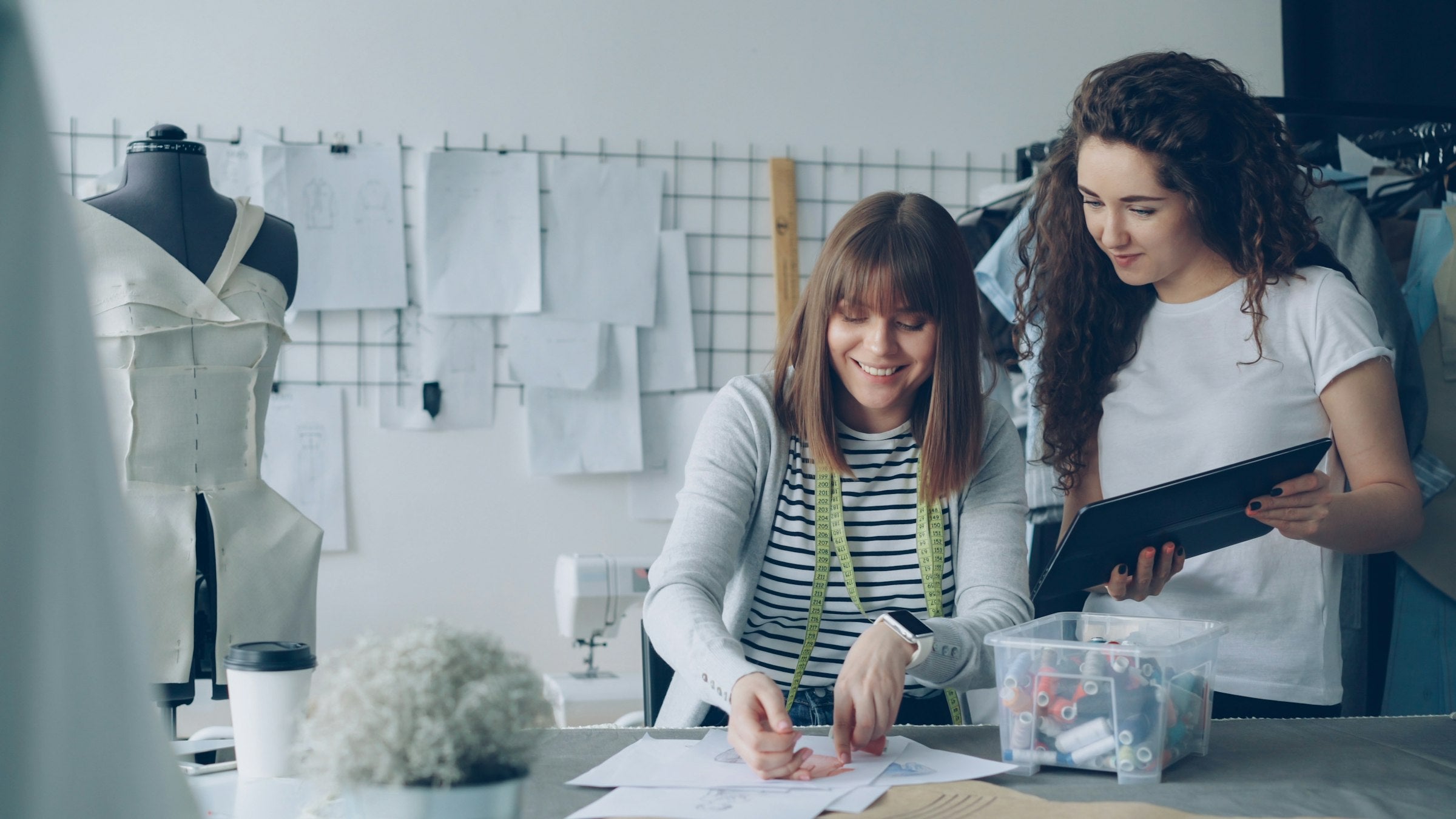 Two people working together in a fashion studio, one showing the other a tablet, representing the working conversation a brand should have with a prospective agency