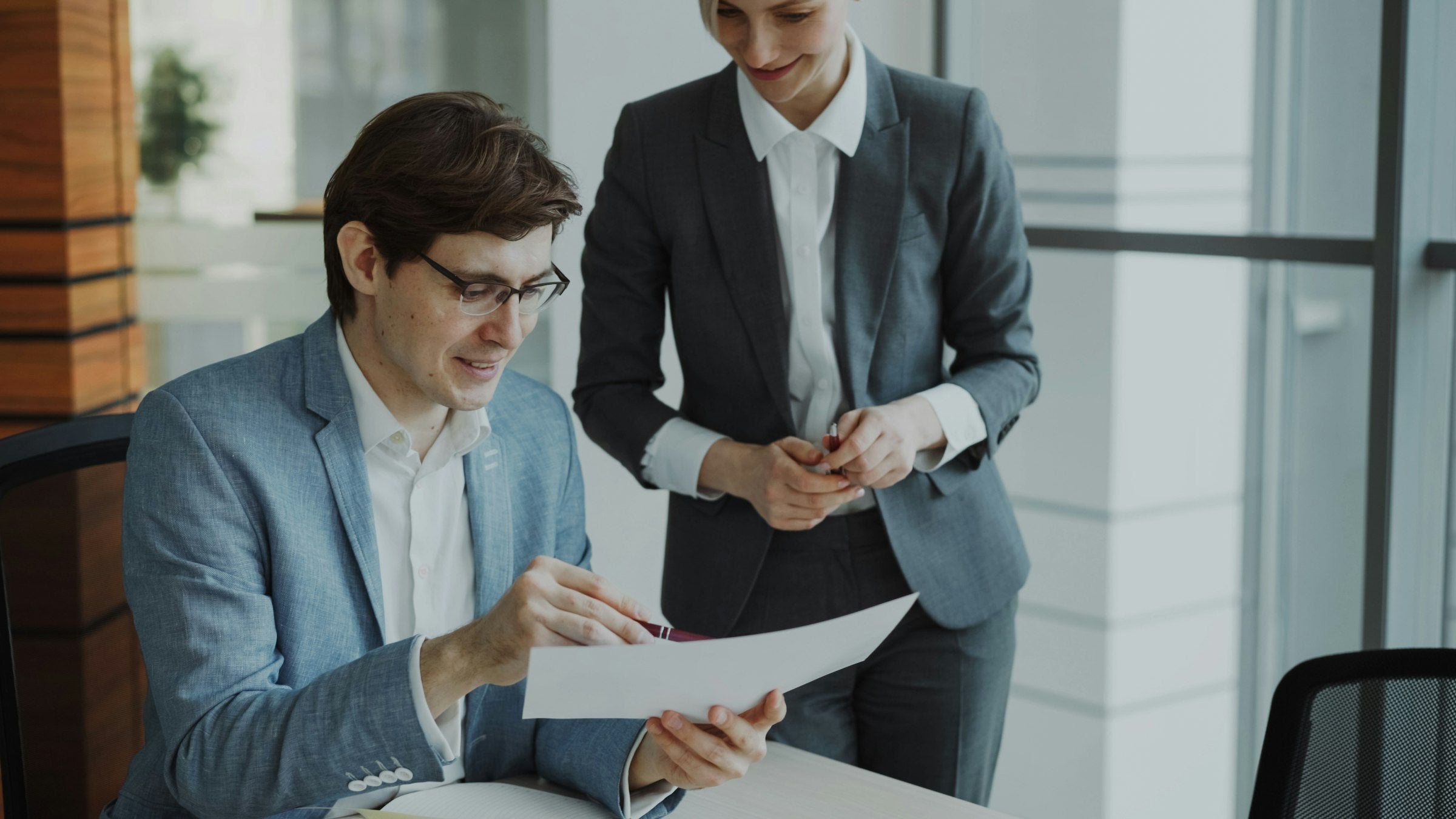 Two business colleagues reviewing printed reports together at a table, representing a brand owner evaluating a prospective growth partner